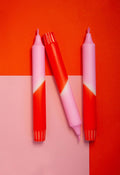 3 dip dye kaarsen in rood en roze kleurverloop op een rood en roze achtergrond.