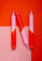 3 dip dye kaarsen in rood en roze kleurverloop op een rood en roze achtergrond.