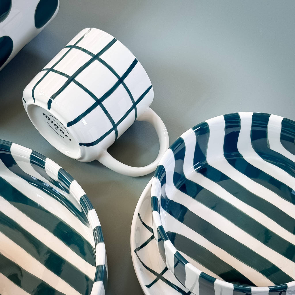 Een close up van servies van Magazin Minori in wit met groen op een groene achtergrond.
