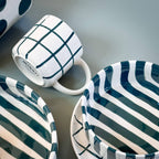 Een close up van servies van Magazin Minori in wit met groen op een groene achtergrond.