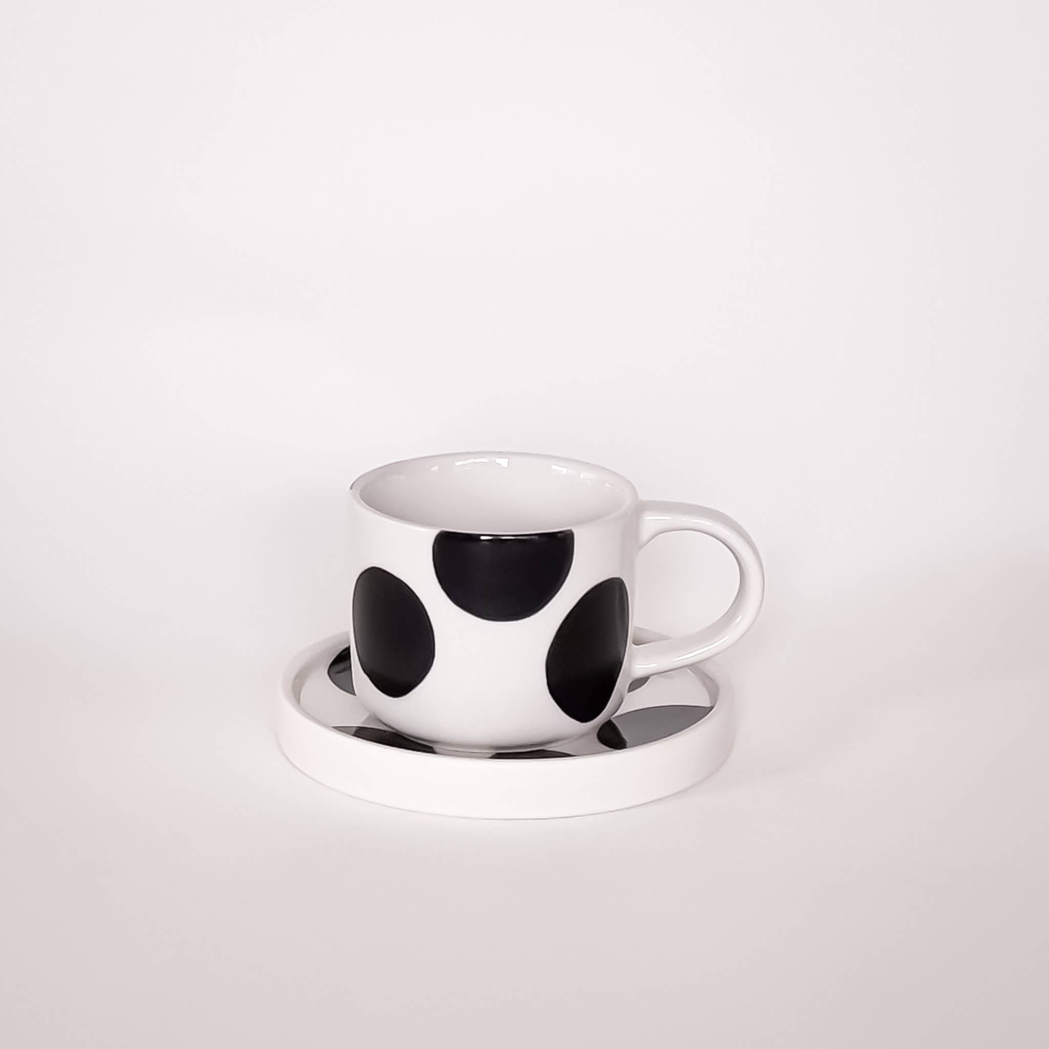 Espresso kop en schotel wit met zwarte stippen op een witte achtergrond