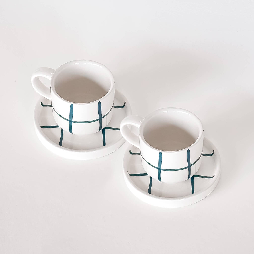 twee espresso kop en schotel in wit met een groen raster patroon op een witte achtergrond