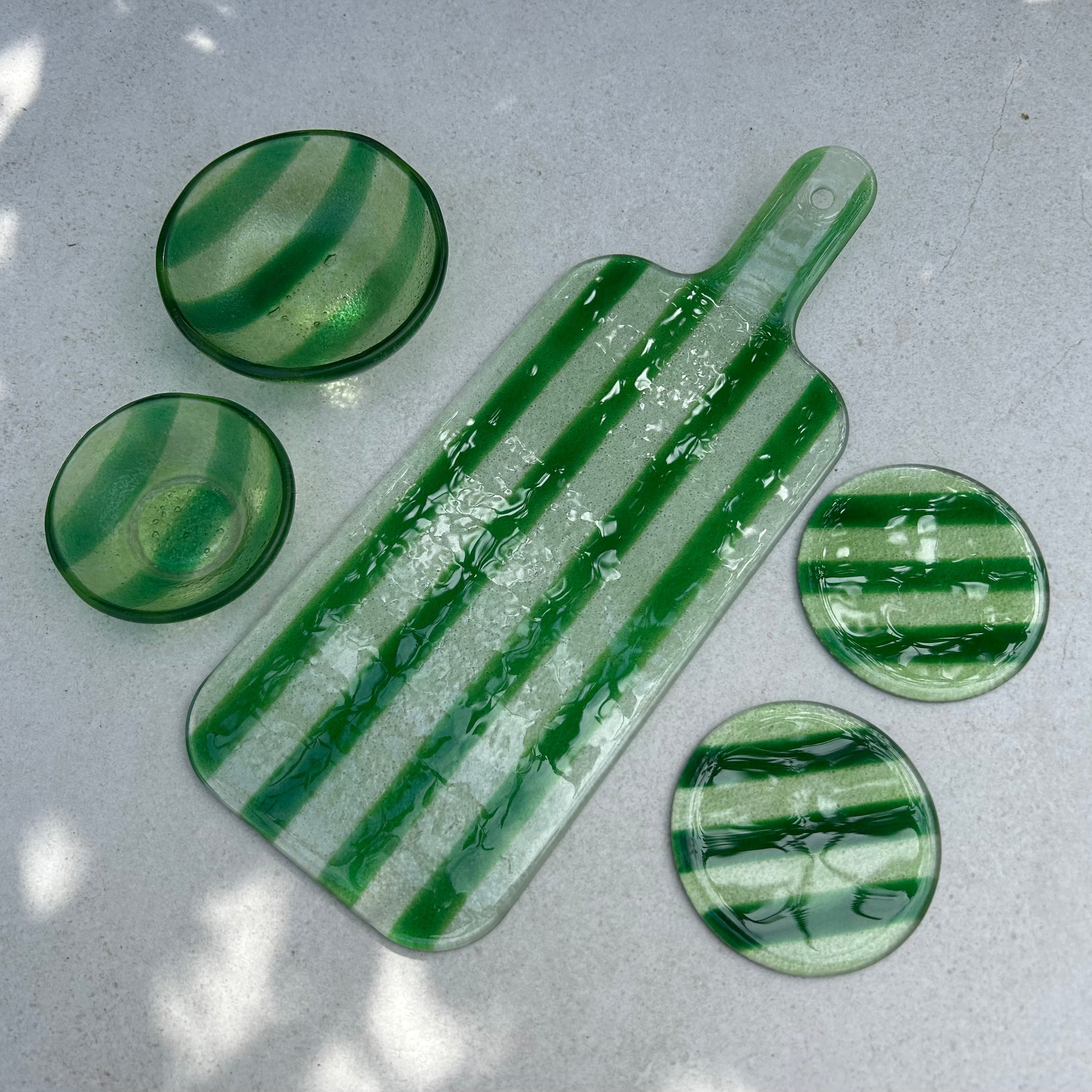 Bovenaanzicht verschillende glazen borrelitems met groene strepen; borrelplank, snackbakjes en onderzetters op een beige achtergrond.