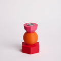 Kandelaar met verwisselbare componenten in de kleuren roze, oranje en rood.