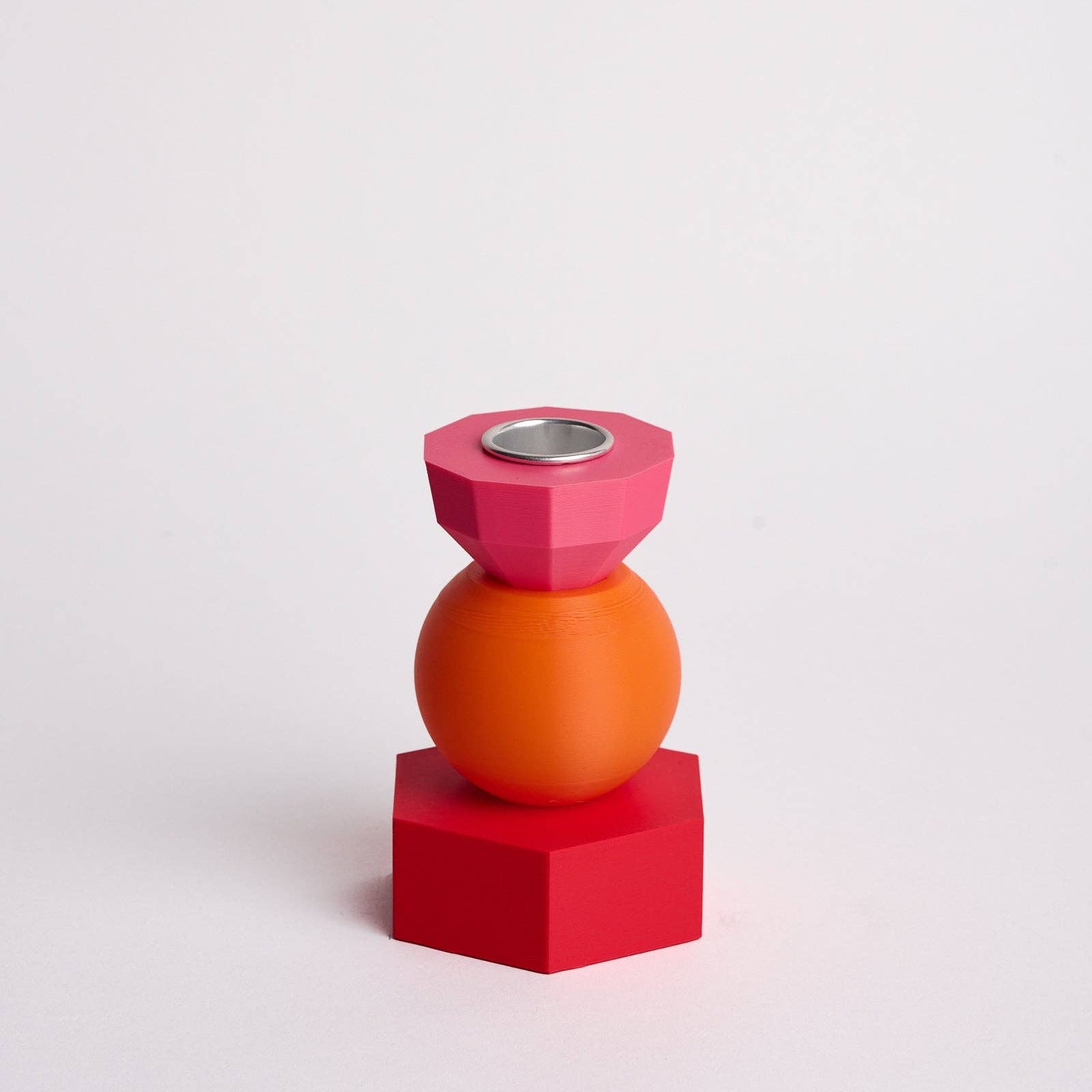 Kandelaar met verwisselbare componenten in de kleuren roze, oranje en rood.