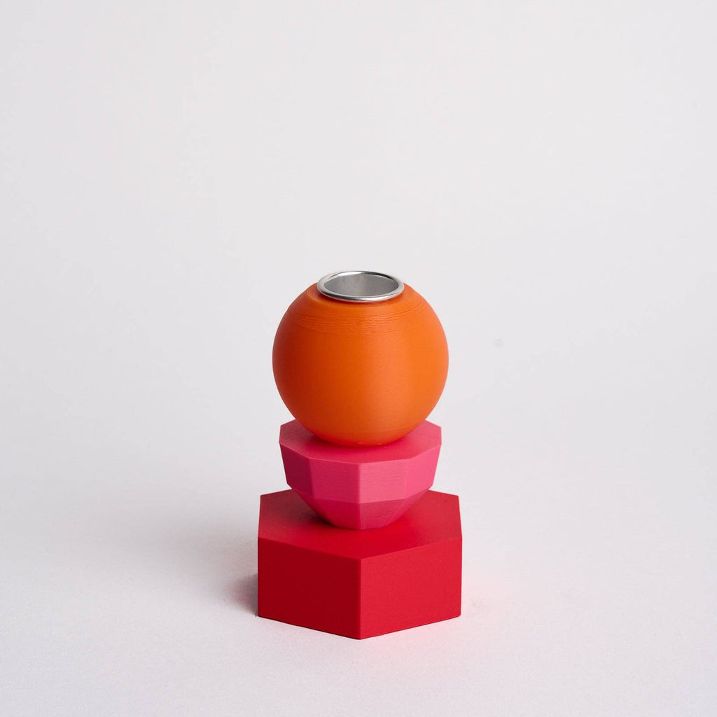 Kandelaar met verwisselbare componenten in de kleuren roze, oranje en rood.