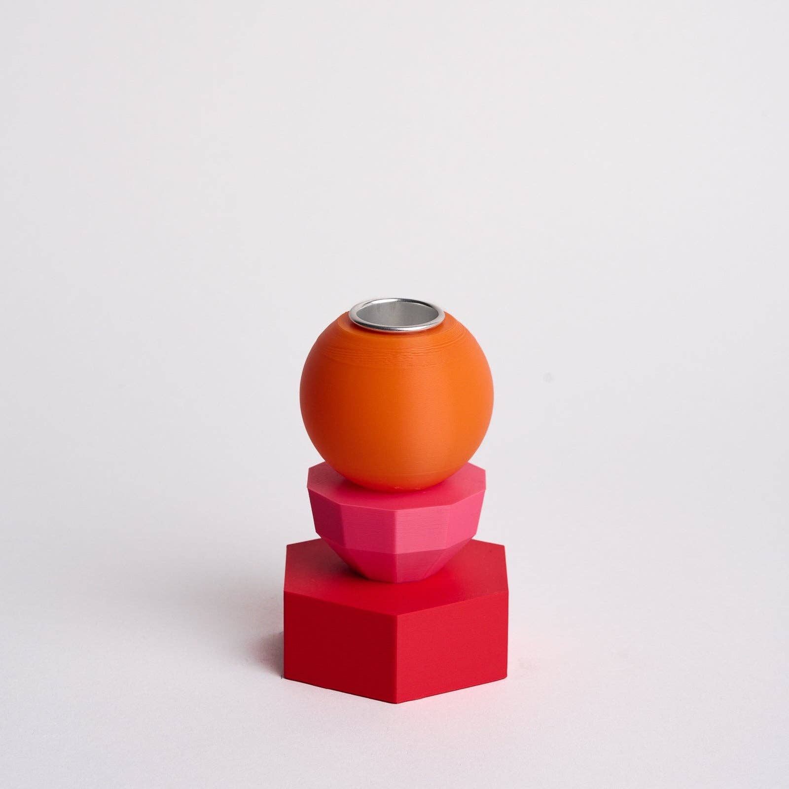 Kandelaar met verwisselbare componenten in de kleuren roze, oranje en rood.