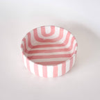 Schaaltje met roze en witte strepen op een witte achtergrond. Bovenaanzicht.