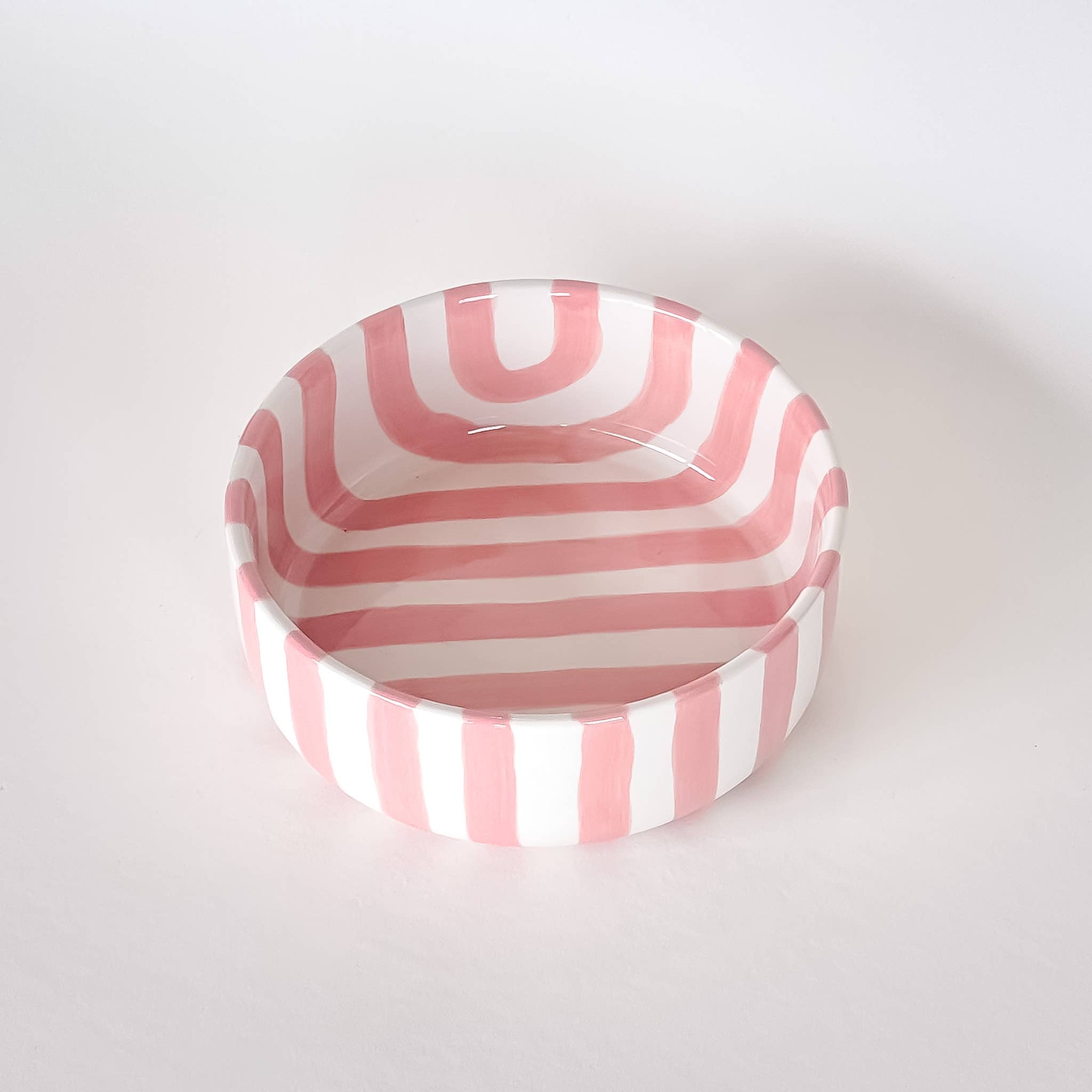 Schaaltje met roze en witte strepen op een witte achtergrond. Bovenaanzicht.