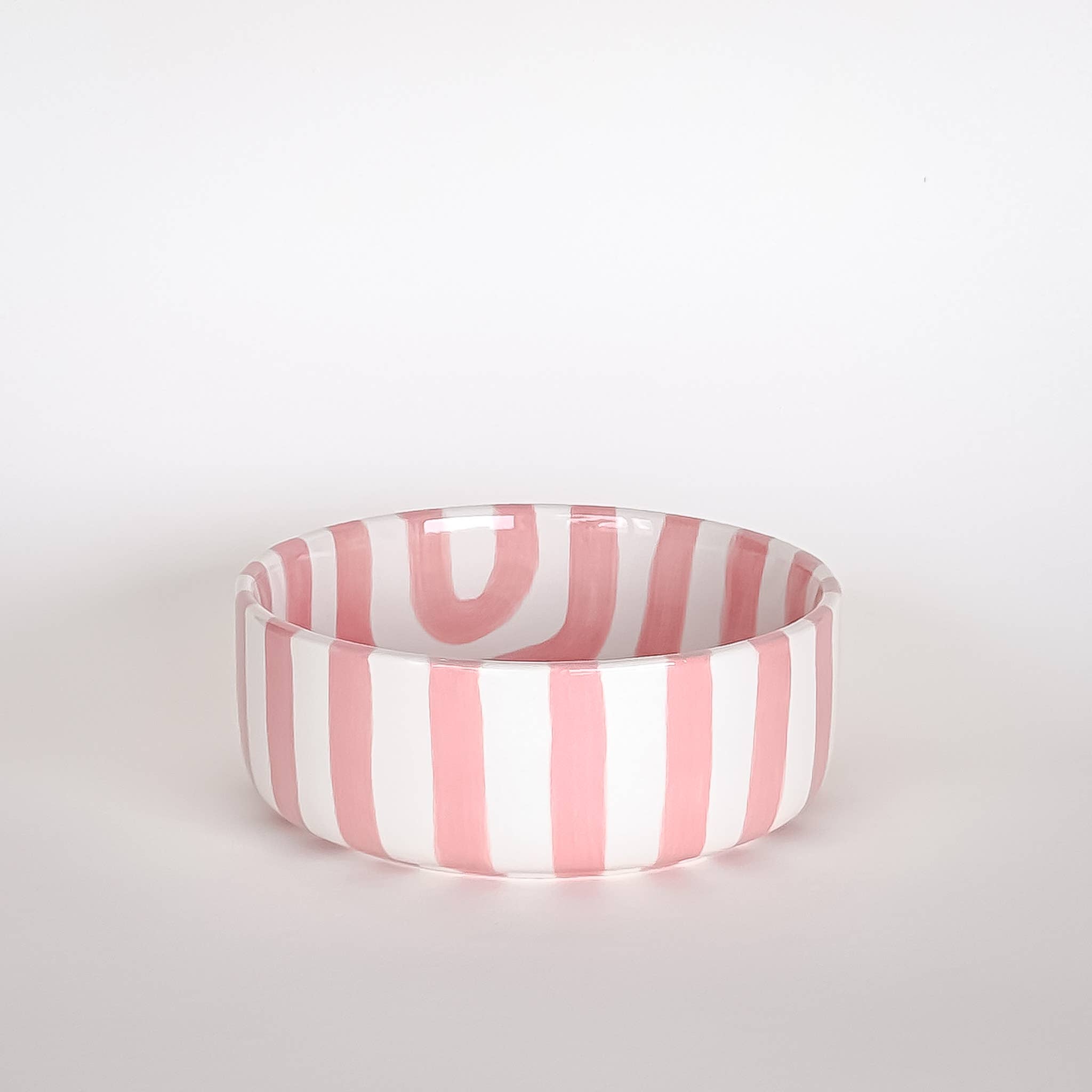 Schaaltje met roze en witte strepen op een witte achtergrond. Vooraanzicht.
