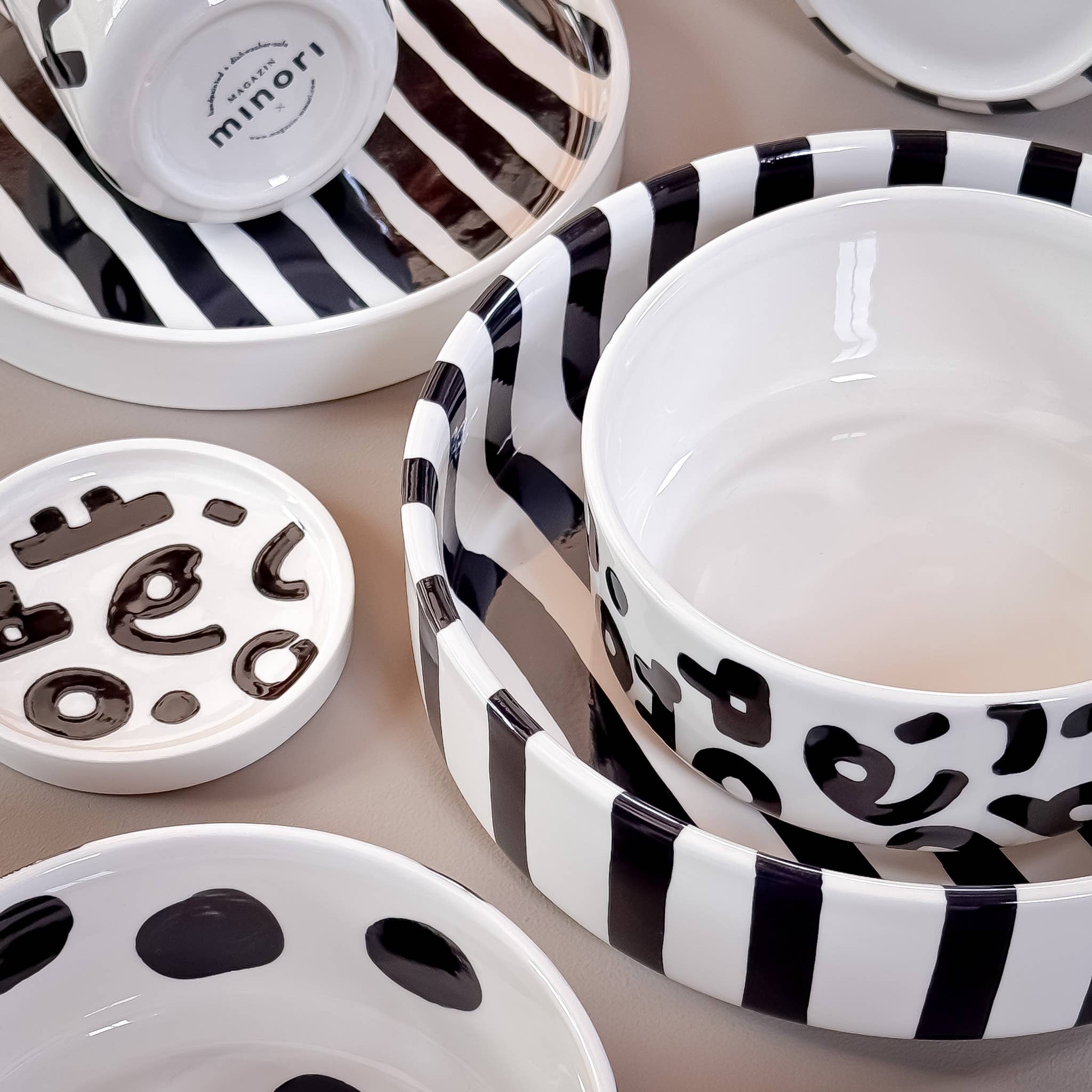 Divers servies van Magazin Minori in zwart wit met verschillende patronen op een beige achtergrond.