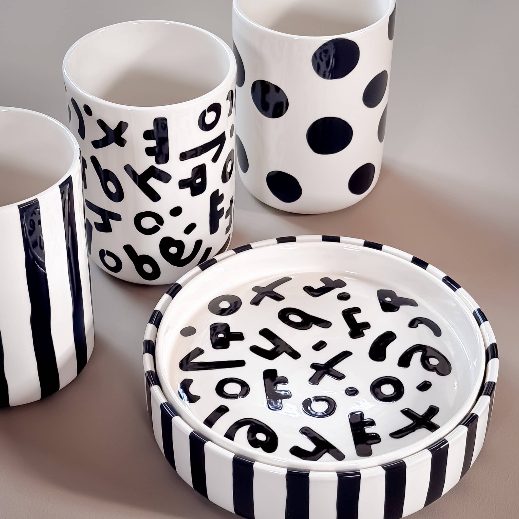 Divers servies van Magazin Minori in zwart wit met verschillende patronen op een beige achtergrond.