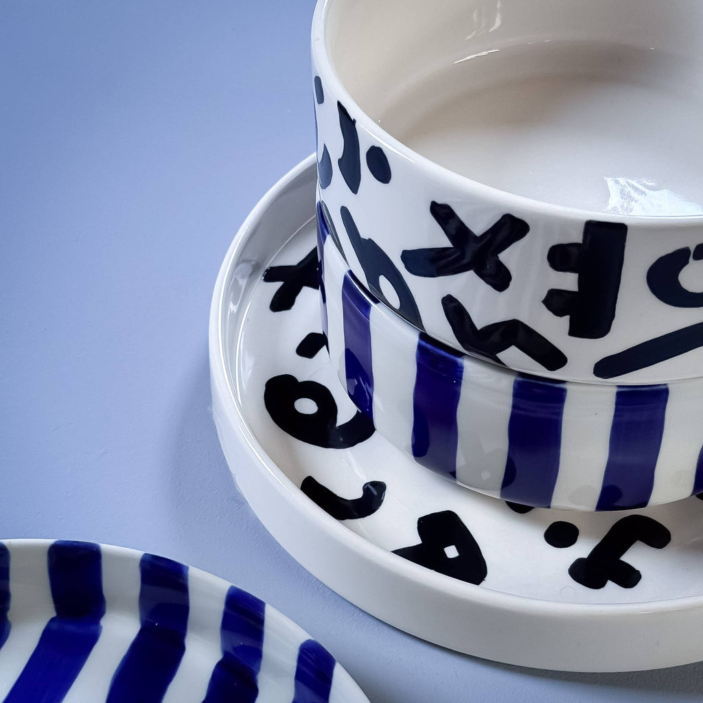 Divers servies van Magazin Minori in zwart wit en blauw wit met verschillende patronen op een lichtblauwe achtergrond.