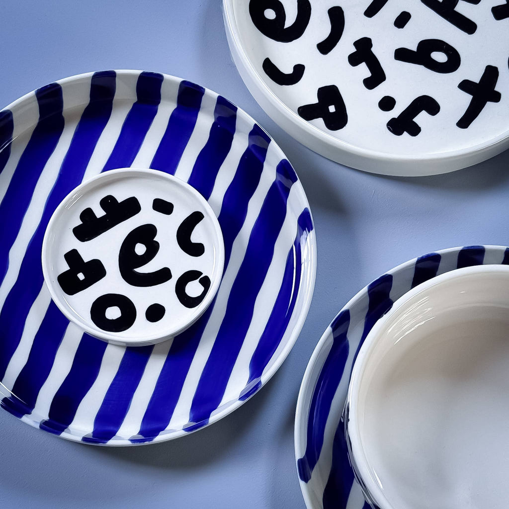 Divers servies van Magazin Minori in zwart wit en blauw wit met verschillende patronen op een lichtblauwe achtergrond.