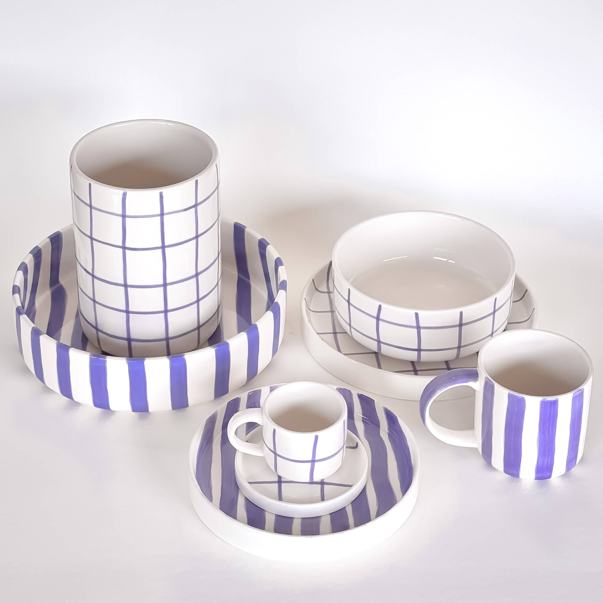 Divers servies van Magazin Minori in wit en paars met diverse patronen op een witte achtergrond.