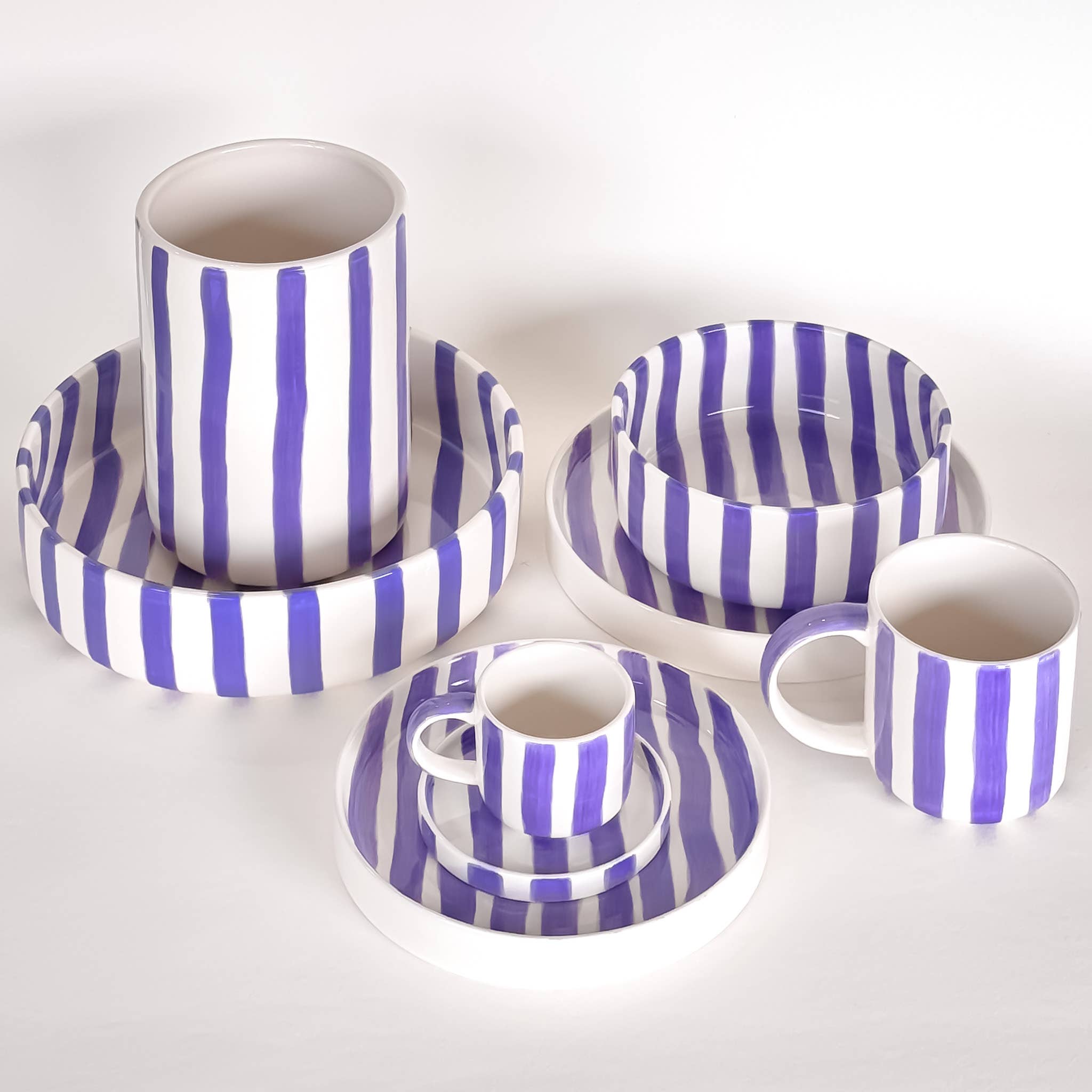 Divers servies van Magazin Minori in paars en wit met strepen op een witte achtergrond.