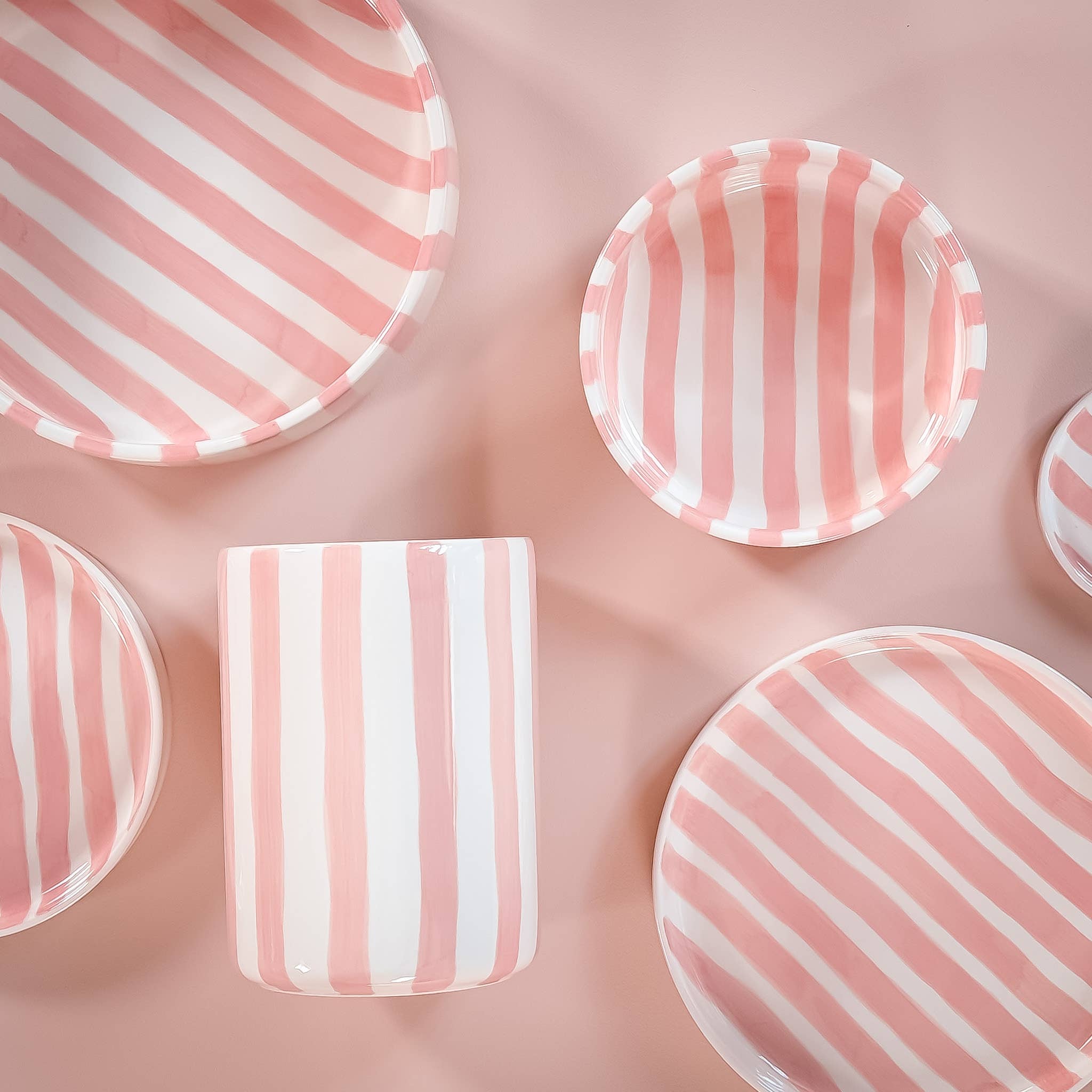 Divers servies van Magazin Minori met roze en witte strepen op een lichtroze achtergrond.