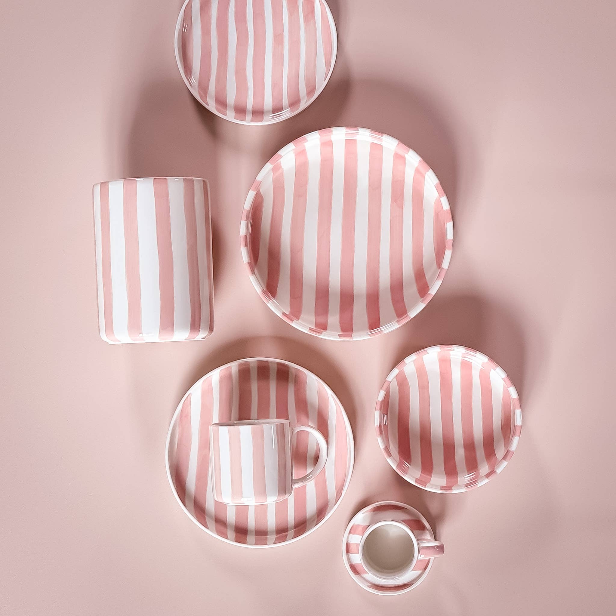 Bovenaanzicht divers servies van Magazin Minori met roze en witte strepen op een lichtroze achtergrond.