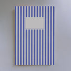 Notitieboek met blauwe verticale lijnen op een witte achtergrond.