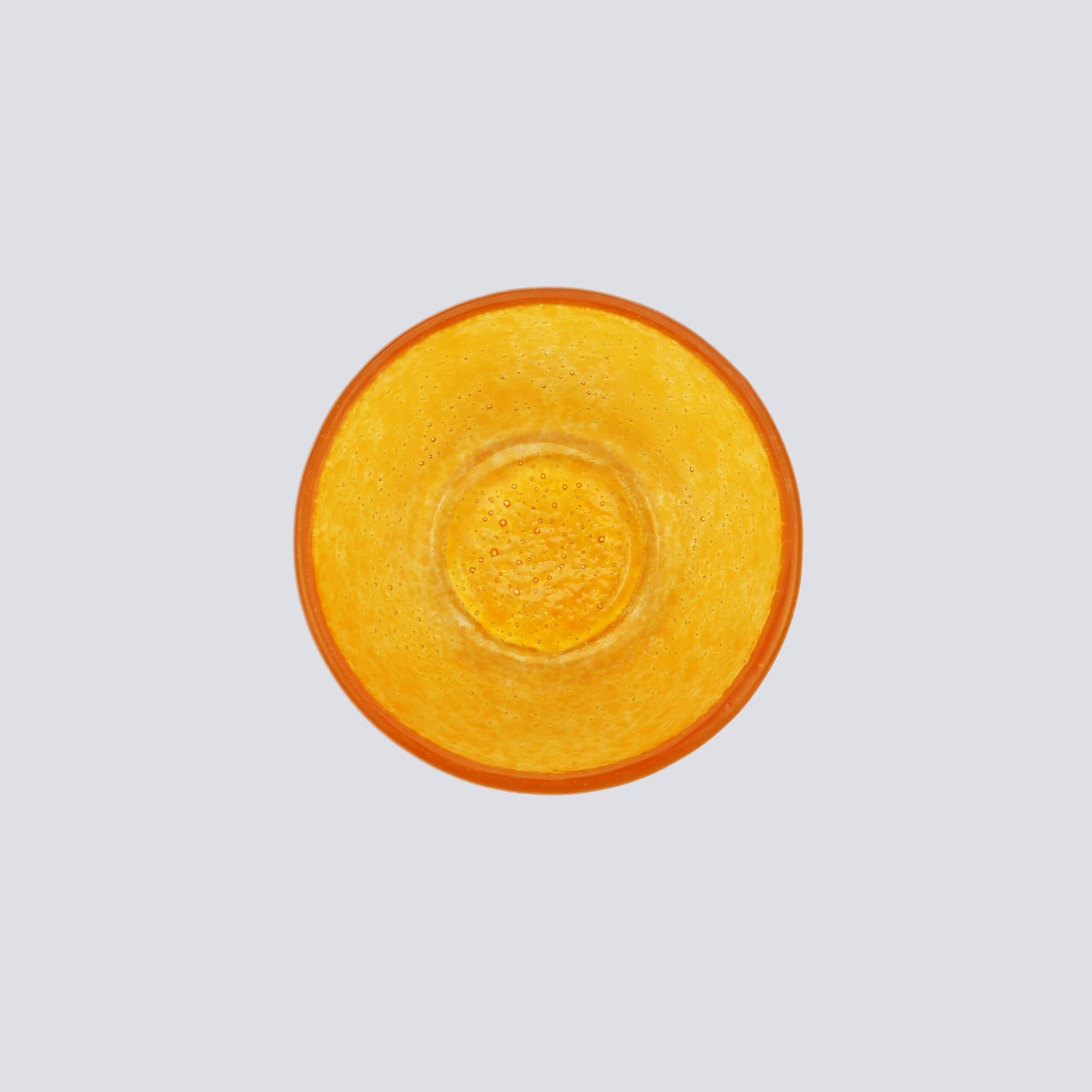 Bovenaanzicht glazen oranje effen schaaltje op een witte achtergrond.