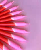 meerdere dip dye kaarsen in rood en roze kleurverloop op een rood en roze achtergrond.