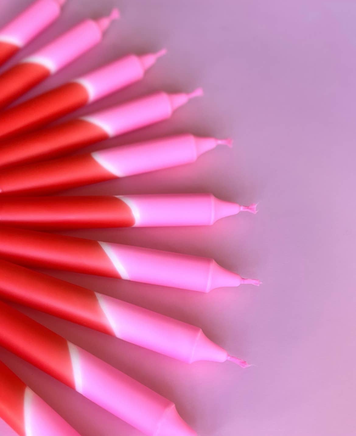 meerdere dip dye kaarsen in rood en roze kleurverloop op een rood en roze achtergrond.