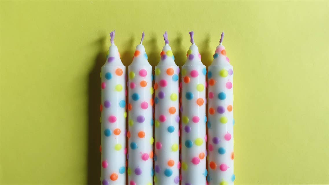 5 Witte handgemaakte dip dye kaarsen met confetti stippen in pastel kleuren op een gele achtergrond