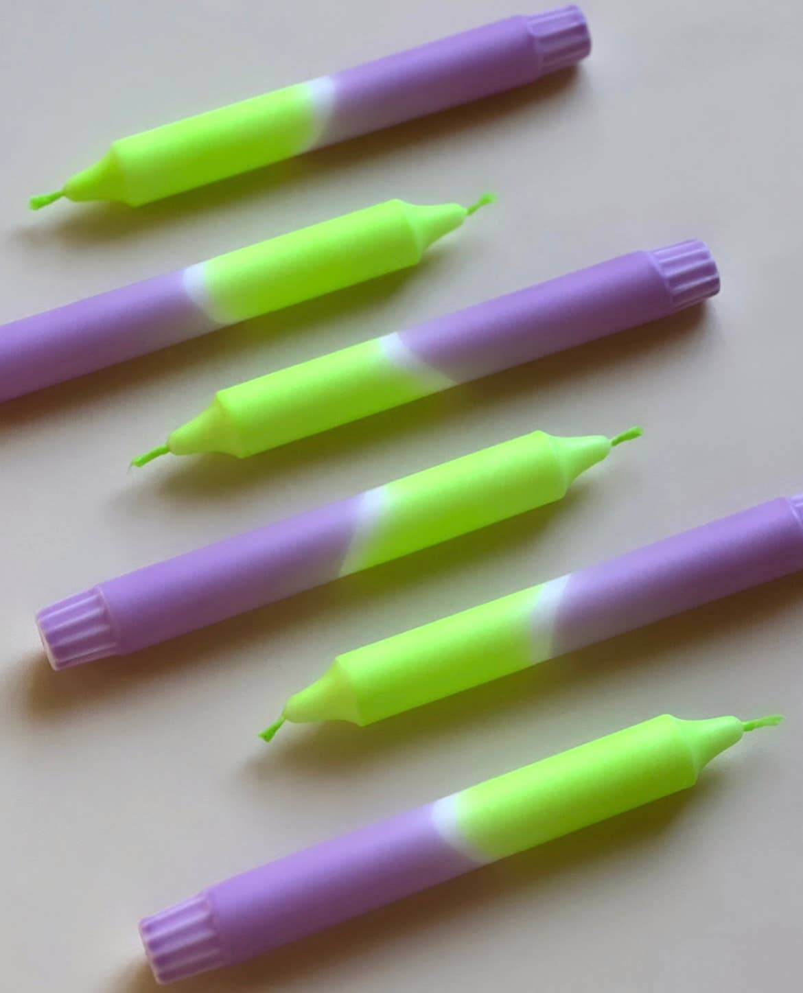 6 dip dye kaarsen in felle neonkleuren groen en paars op een beige achtergrond